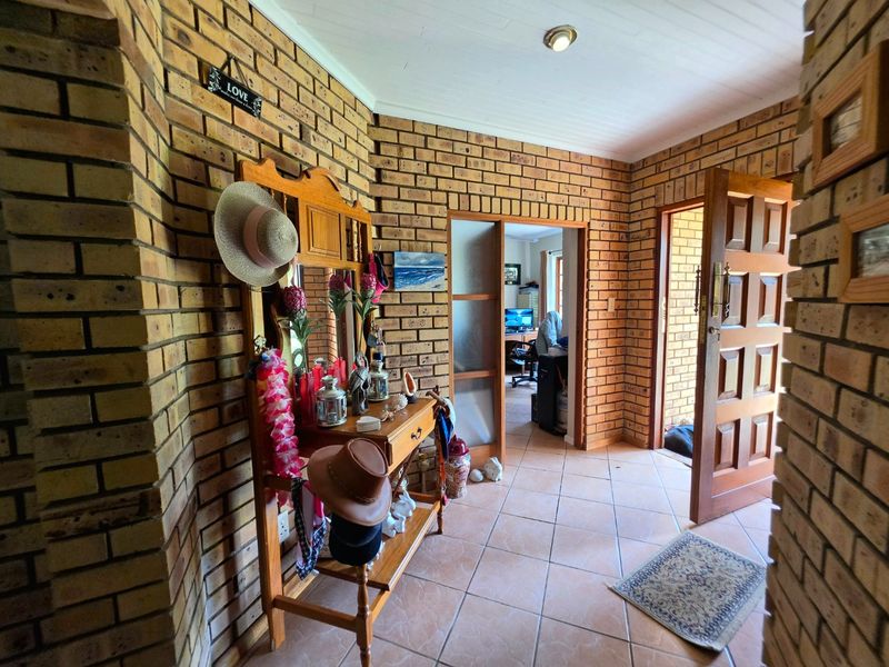 Entrance hall featuring exposed brick walls, tiled flooring, and timber panelled ceiling, providing access to adjacent living spaces.