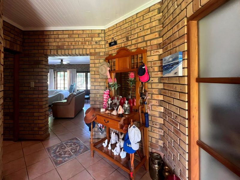 Entrance hall featuring rustic exposed brick walls, tiled flooring, and a timber-framed door leading into the main living area.