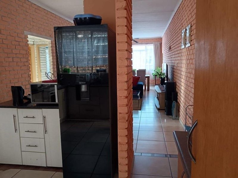 Open-plan living area featuring exposed brick walls and tiled flooring, connecting the kitchen space to the main living area.