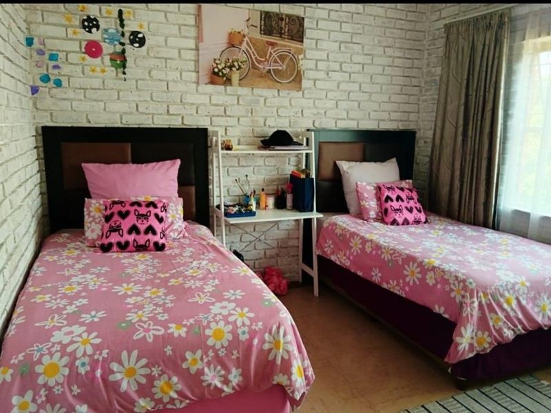 A bedroom featuring an exposed white-painted brick wall and window with curtain tracks, providing a textured backdrop for the space.