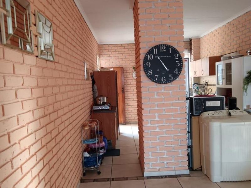 Kitchen area featuring exposed brick walls and tiled flooring, offering a rustic aesthetic with functional built-in cabinetry.