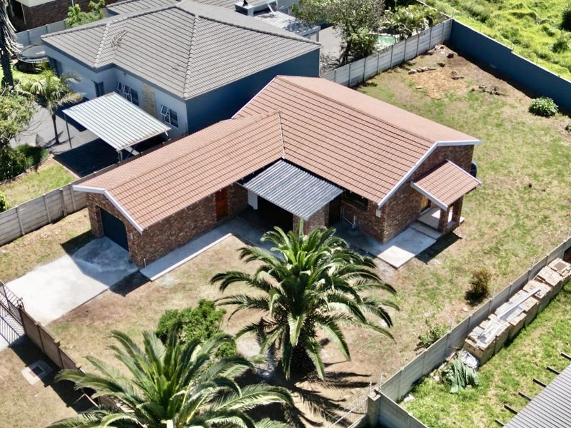 Aerial view of a face brick house featuring a tiled roof, concrete driveway, and a spacious yard enclosed by precast boundary walls.
