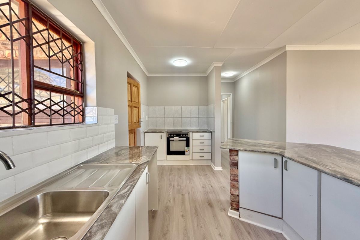 A clean, functional kitchen featuring laminate countertops, built-in oven, hob, subway tile backsplash, and durable laminate flooring.
