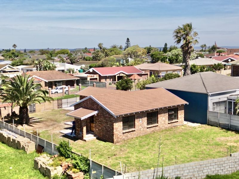 Aerial view of a face-brick residential property featuring a tiled roof, surrounding perimeter wall with electric fencing, and a spacious garden area.