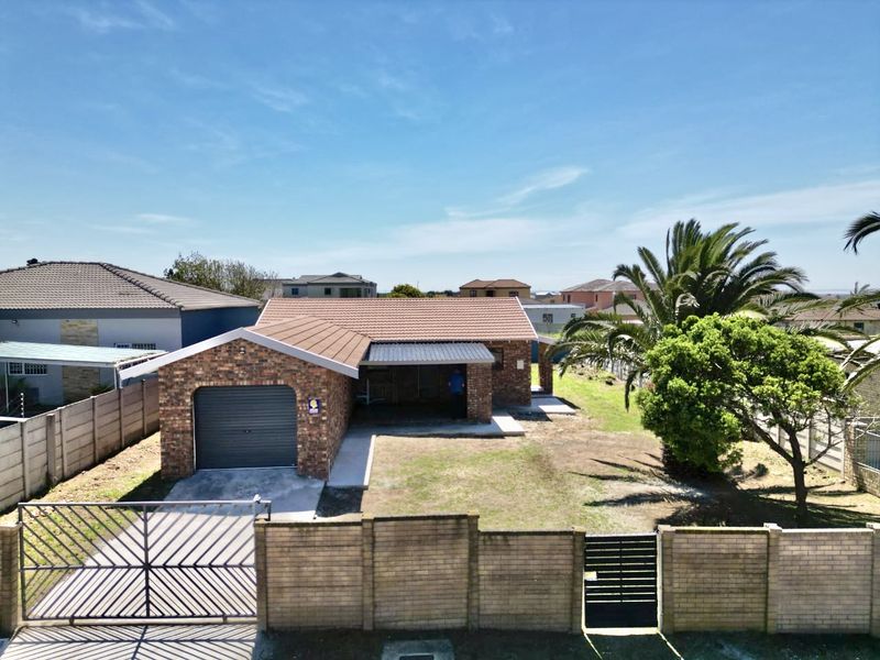 Front view of a single-story brick house featuring a single garage, covered patio, and a gated entrance with a paved driveway.