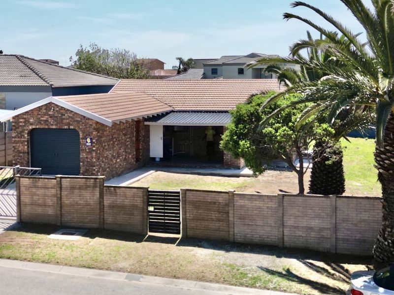 Front view of a face brick house featuring a single garage, tiled roof, and perimeter boundary wall with gated access.