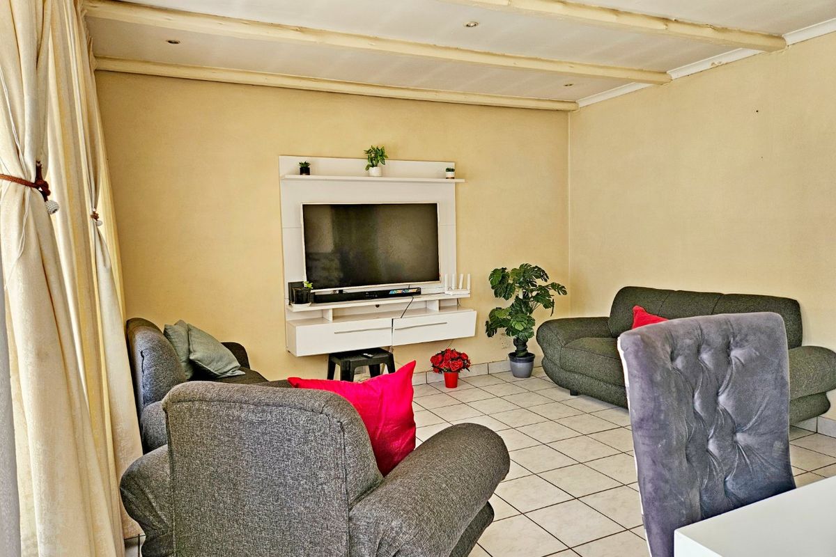 A living room featuring tiled flooring and a built-in media console, with exposed ceiling beams providing a distinct architectural element.