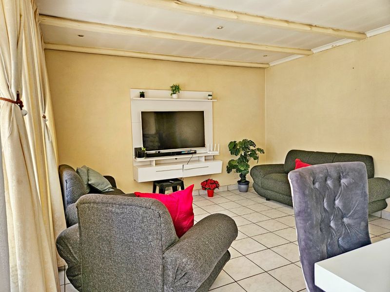 A living room featuring tiled flooring and a built-in media console, with exposed ceiling beams providing a distinct architectural element.