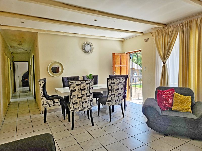 Open plan living and dining area featuring tiled flooring, exposed ceiling beams, and direct access to the outdoor patio area.