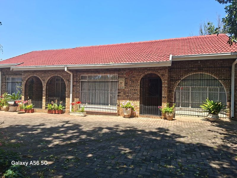Front elevation of a face brick house featuring a tiled roof, arched architectural details, and a paved driveway area.