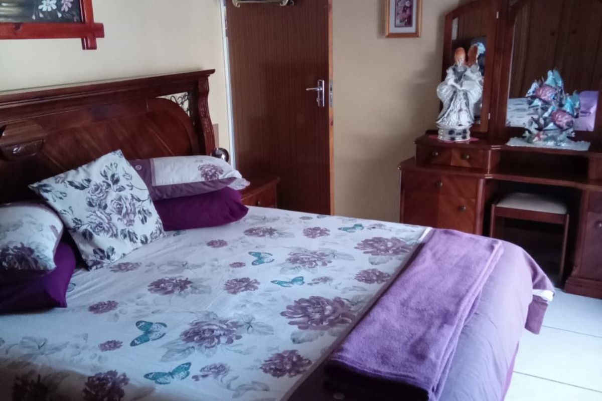 A functional bedroom featuring tiled flooring and a solid wood door, providing a neutral base for potential interior updates.