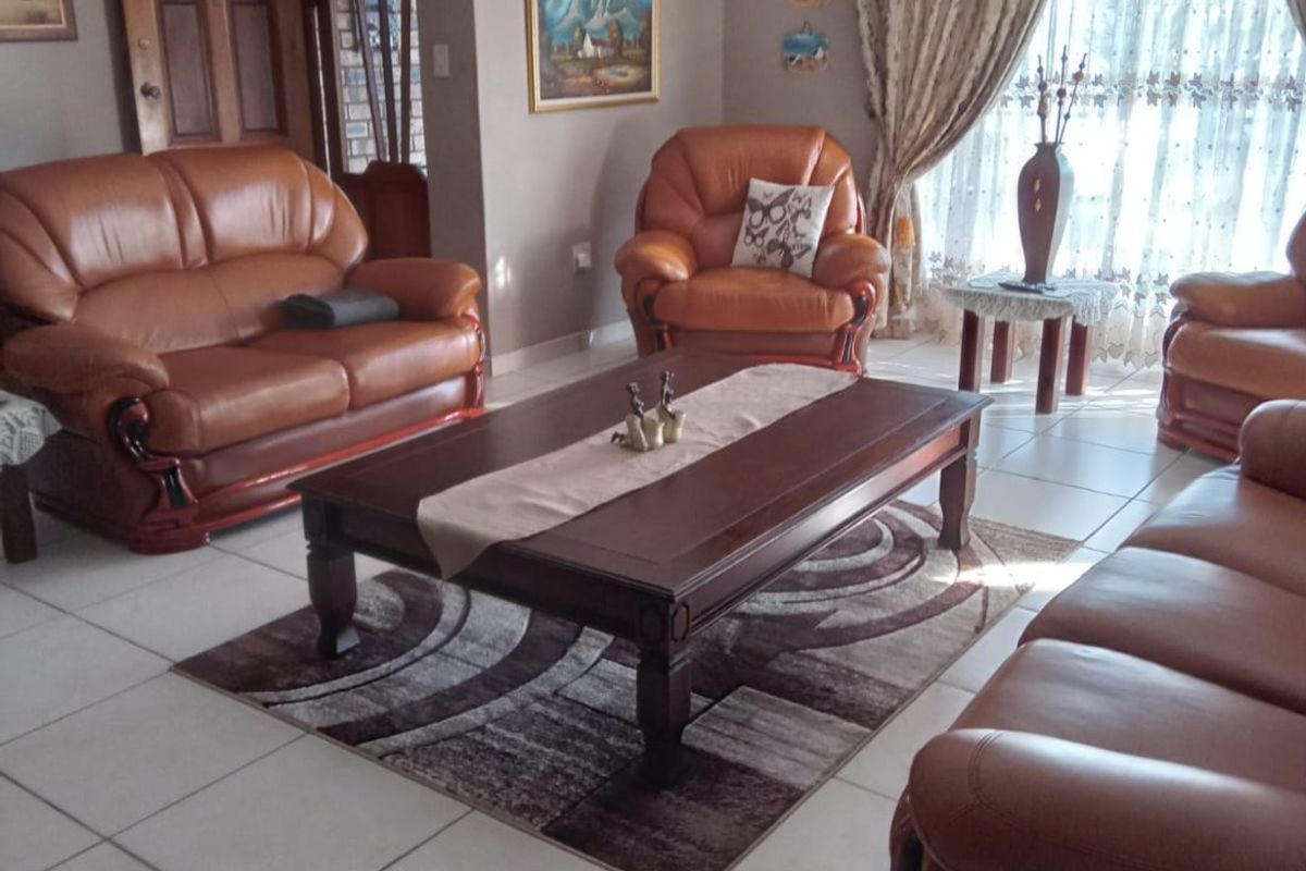 A spacious living room featuring neutral wall tones, tiled flooring, and a ceiling fan, offering a comfortable and functional family living space.
