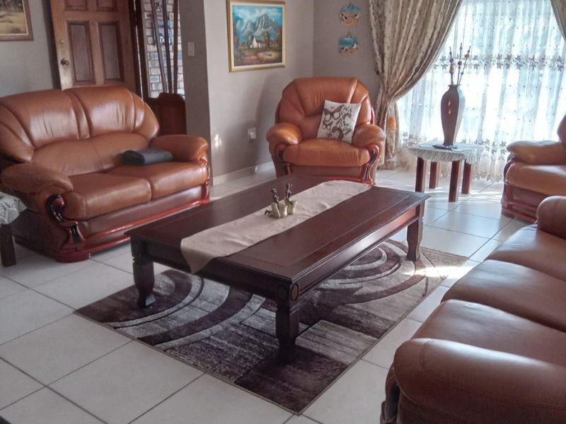 A spacious living room featuring neutral wall tones, tiled flooring, and a ceiling fan, offering a comfortable and functional family living space.