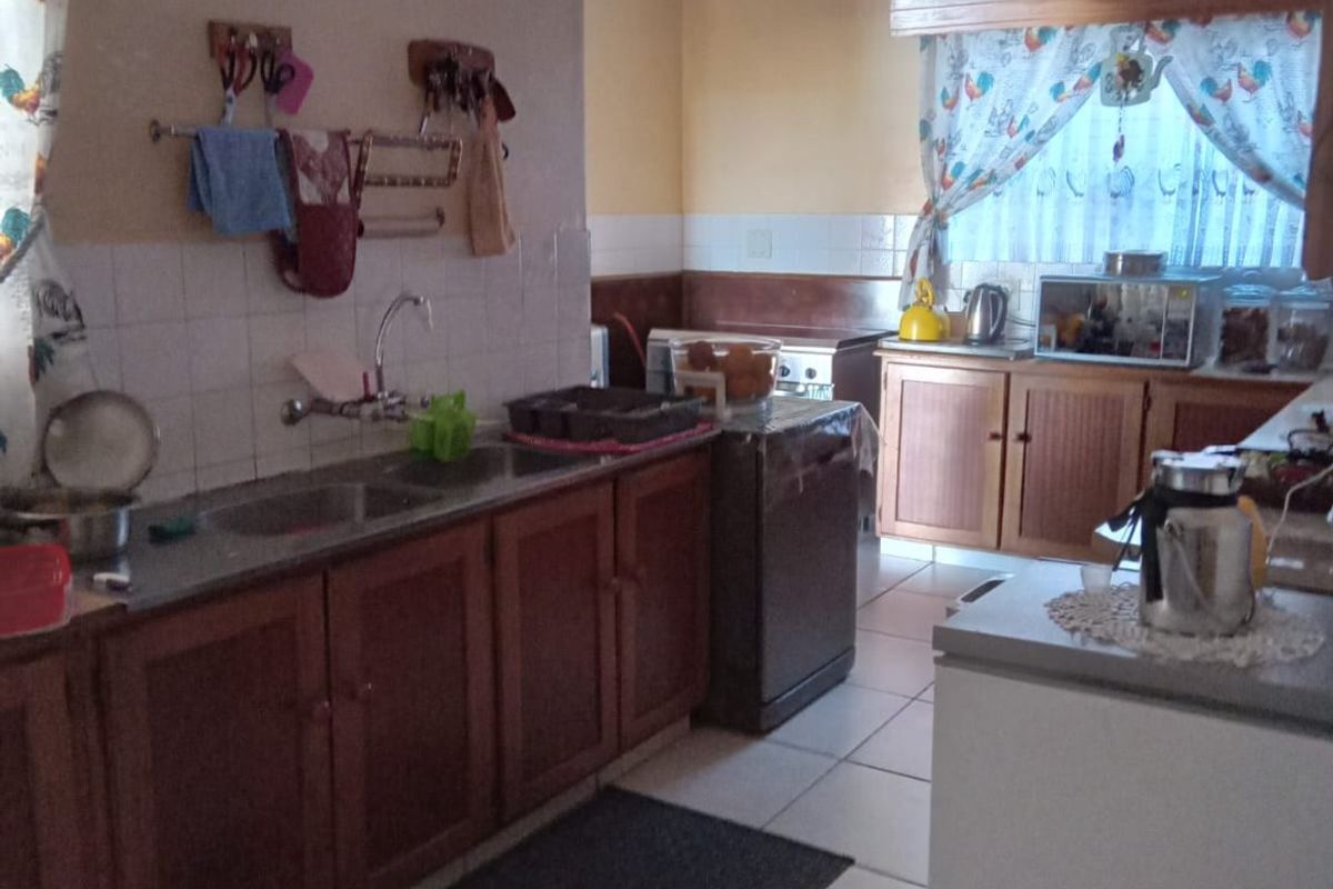 A functional kitchen featuring wooden cabinetry, tiled flooring, and a tiled backsplash, offering a traditional layout with ample counter space.