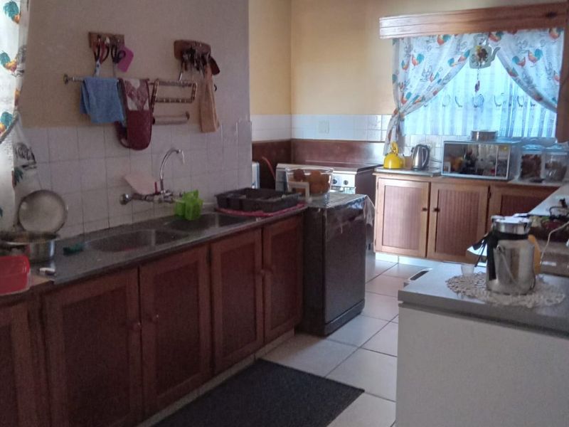 A functional kitchen featuring wooden cabinetry, tiled flooring, and a tiled backsplash, offering a traditional layout with ample counter space.
