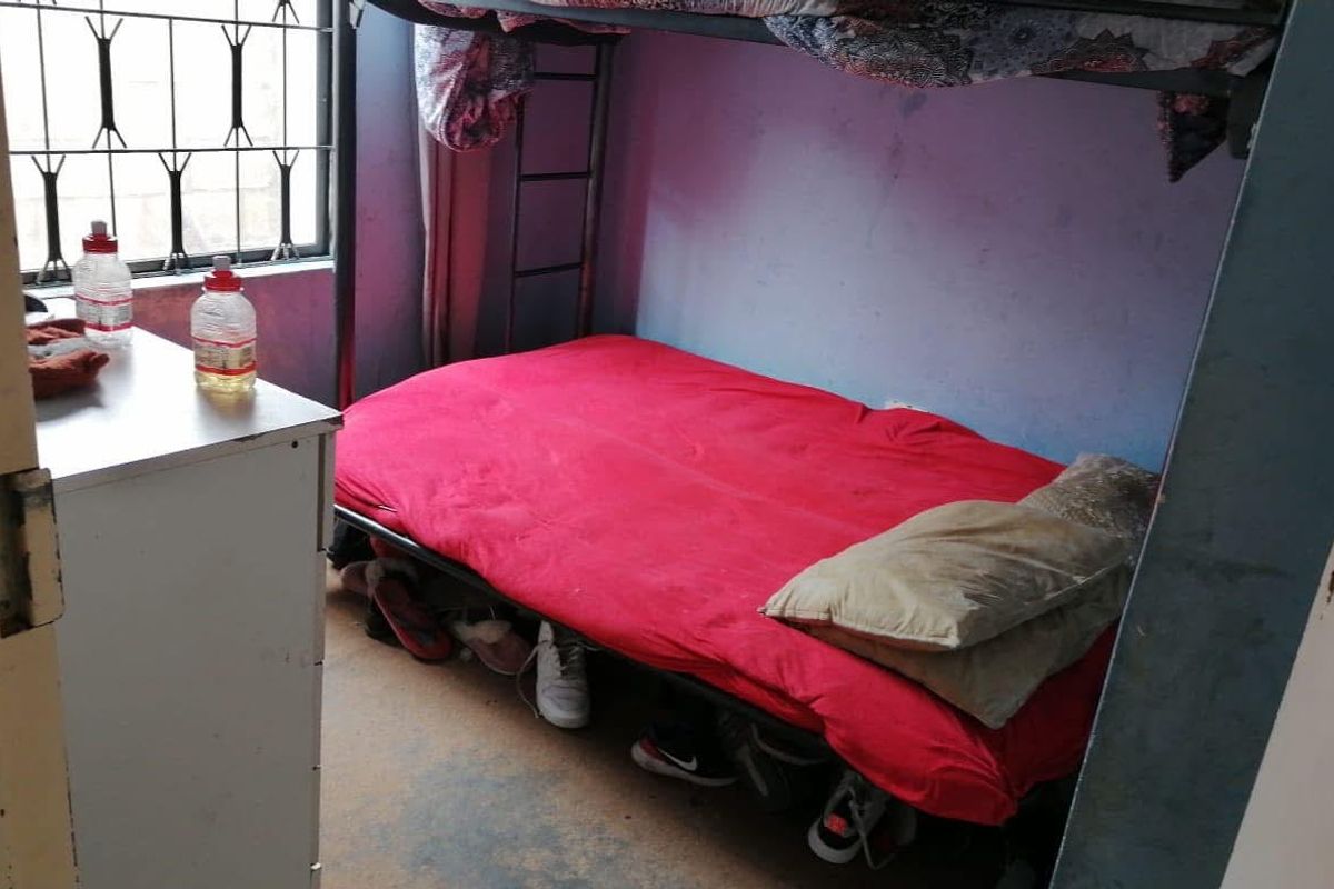 A compact bedroom featuring security bars on the window and basic finishes, suitable for a renovation to improve the overall aesthetic and condition.