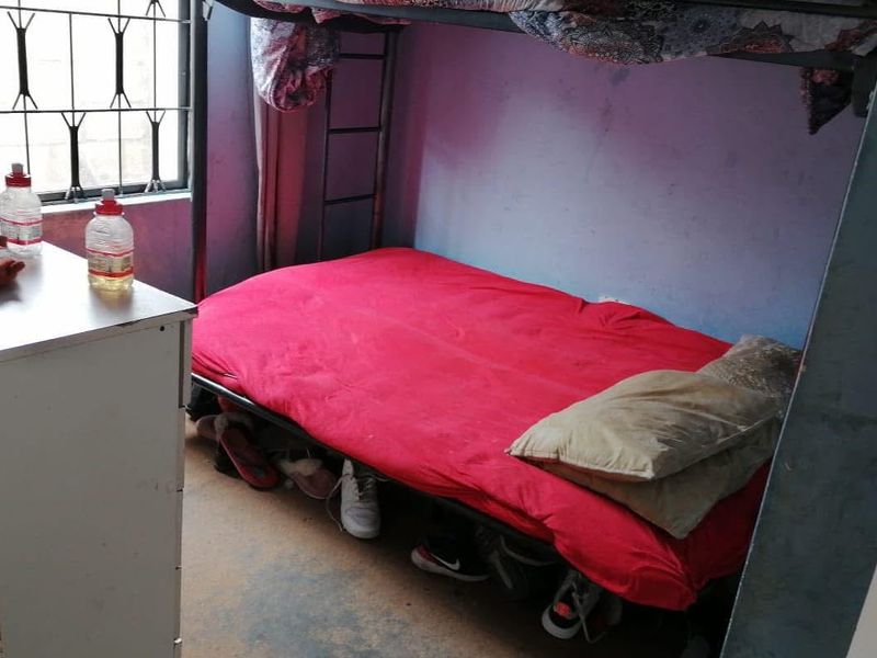 A compact bedroom featuring security bars on the window and basic finishes, suitable for a renovation to improve the overall aesthetic and condition.