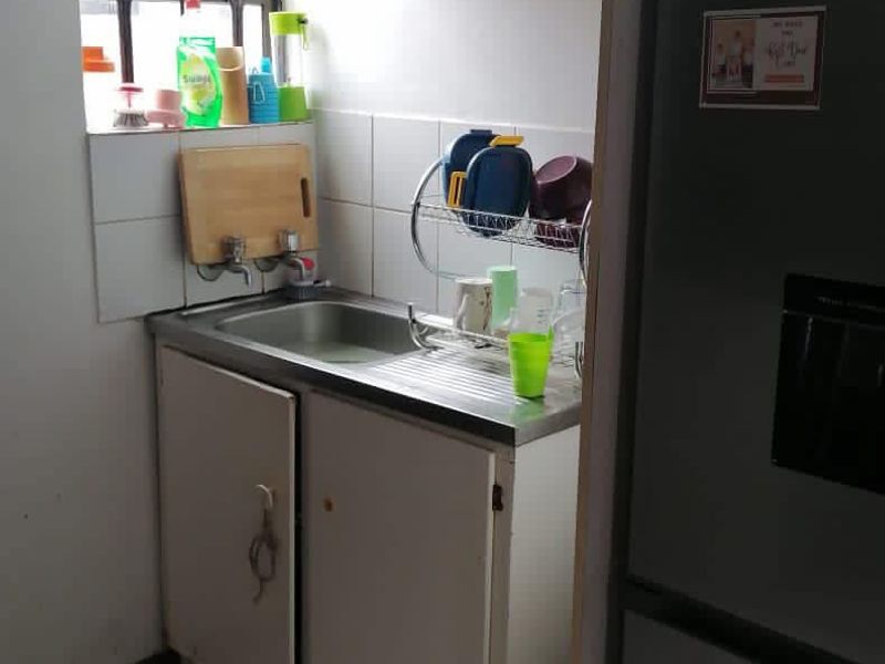 Compact scullery area featuring a stainless steel sink, built-in cabinetry, and tiled splashback, providing functional utility space.