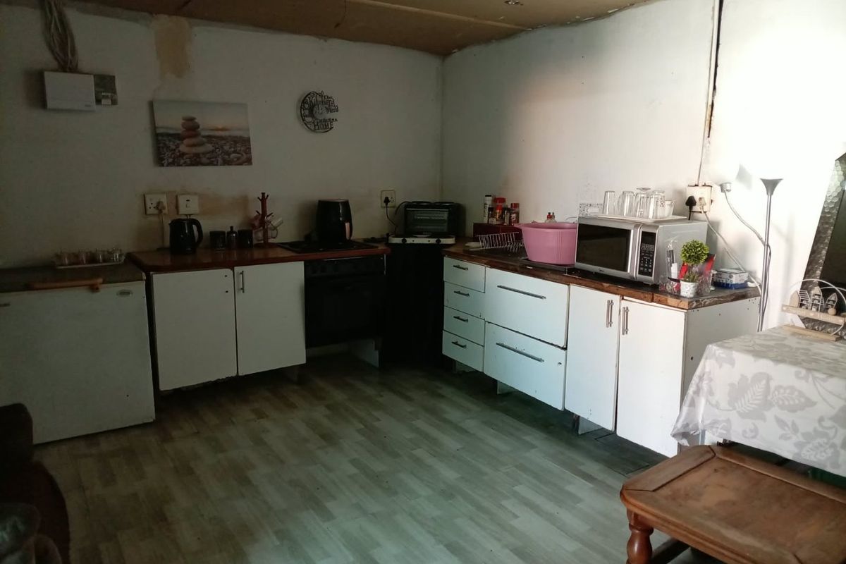 A dated kitchen area featuring basic cabinetry and laminate countertops, currently requiring significant renovation and cosmetic updates to improve functionality and aesthetic appeal.