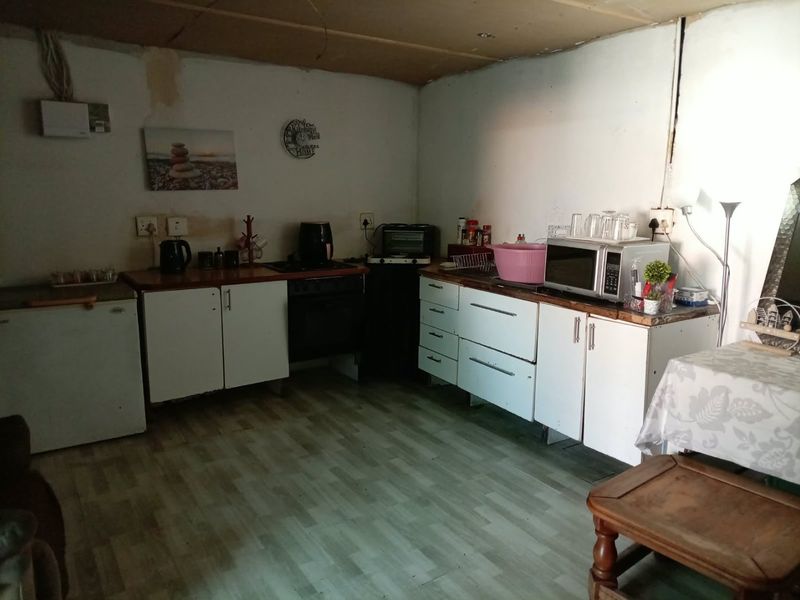 A dated kitchen area featuring basic cabinetry and laminate countertops, currently requiring significant renovation and cosmetic updates to improve functionality and aesthetic appeal.