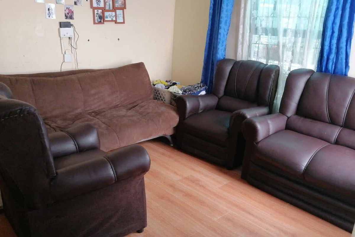 A living room area featuring laminate flooring and window security bars, providing a functional space for relaxation.