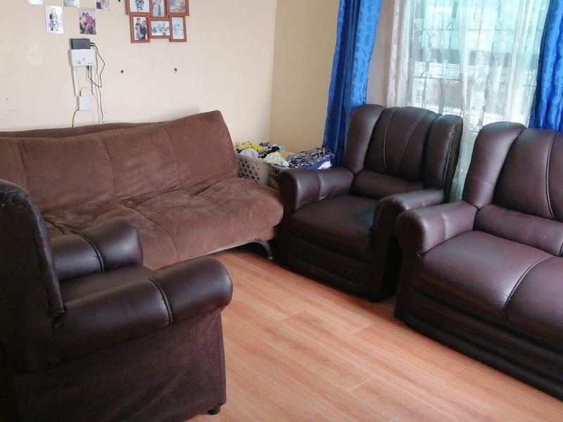 A living room area featuring laminate flooring and window security bars, providing a functional space for relaxation.