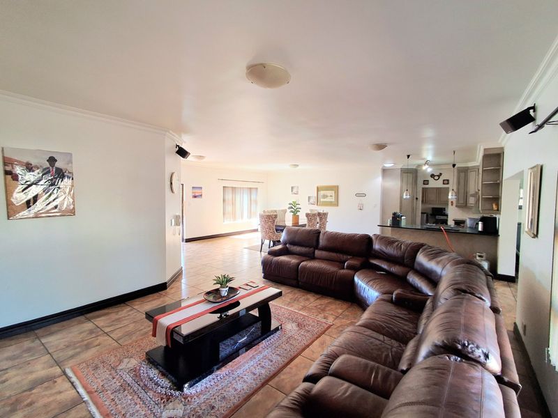 Spacious open-plan living and dining area featuring tiled flooring and a functional kitchen with built-in cabinetry and island.