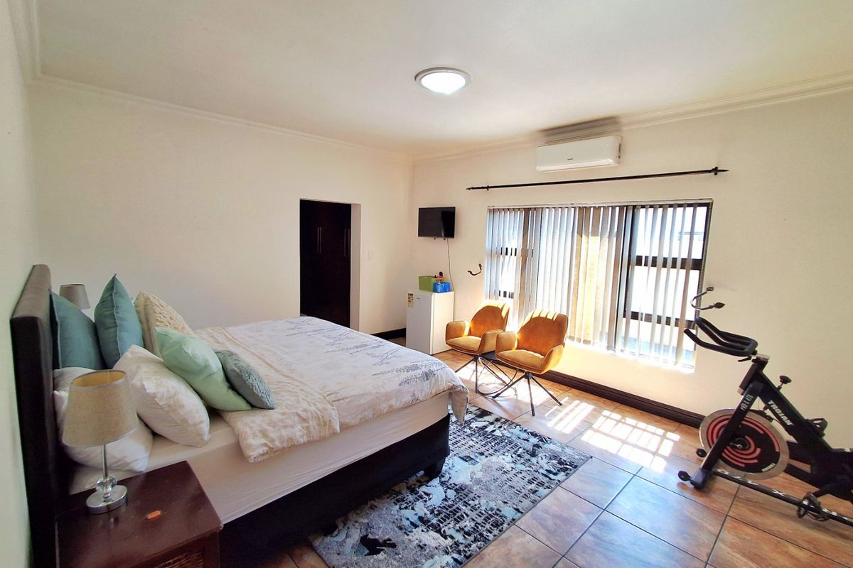 Spacious bedroom featuring tiled flooring, an air conditioning unit, and built-in storage, offering a comfortable and functional living space.
