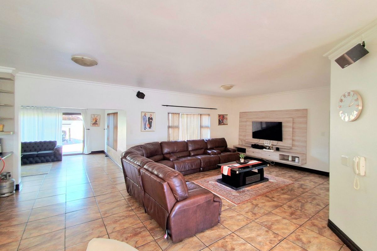 Spacious living room featuring tiled flooring, a built-in media wall unit, and direct access to an outdoor patio area.