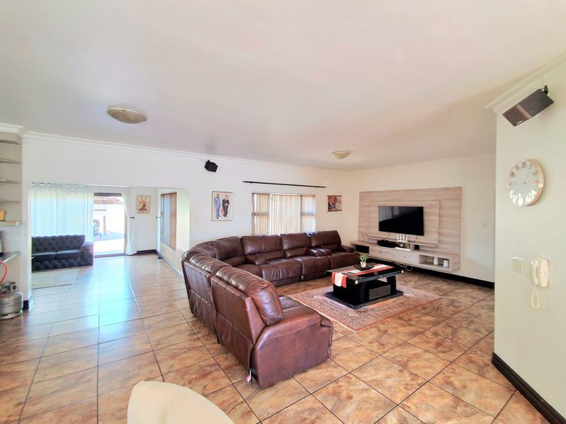 Spacious living room featuring tiled flooring, a built-in media wall unit, and direct access to an outdoor patio area.
