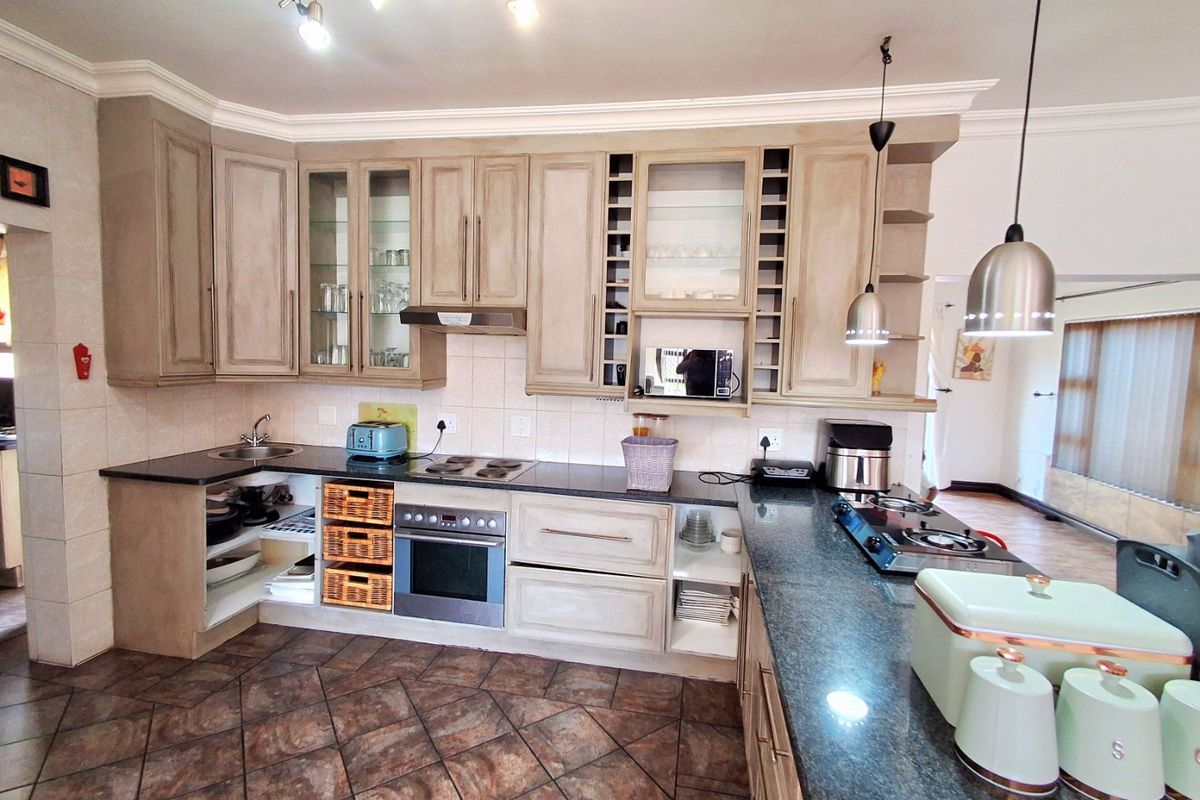 Spacious kitchen featuring granite countertops, dual hobs, built-in oven, and ample cabinetry, offering a functional layout with potential for modern updates.