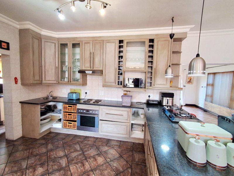 Spacious kitchen featuring granite countertops, dual hobs, built-in oven, and ample cabinetry, offering a functional layout with potential for modern updates.