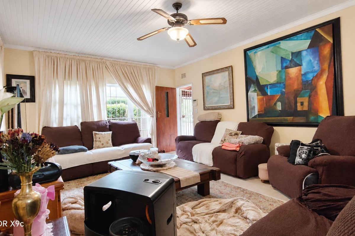 A comfortable living room featuring a tongue and groove ceiling, a central ceiling fan, and direct access to the exterior through a timber door.