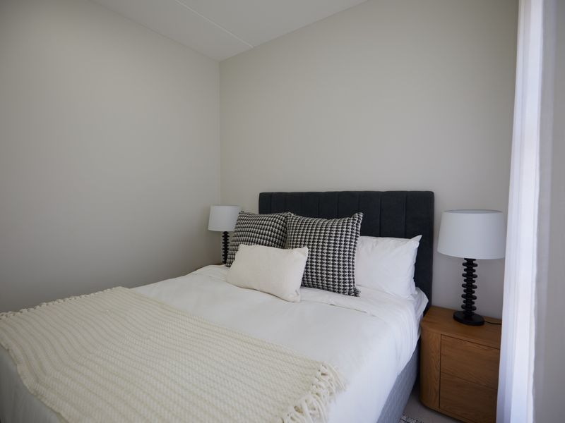 A well-lit, neutral-toned bedroom featuring clean finishes and a comfortable layout.