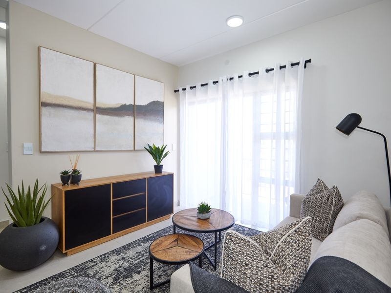 A bright and modern living room featuring tiled flooring, recessed ceiling lighting, and a large sliding glass door with sheer curtains.