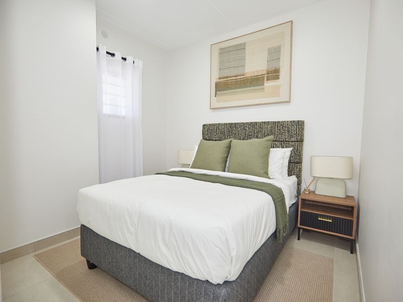 A well-maintained bedroom featuring neutral tiled flooring and clean white walls, providing a bright and comfortable living space.