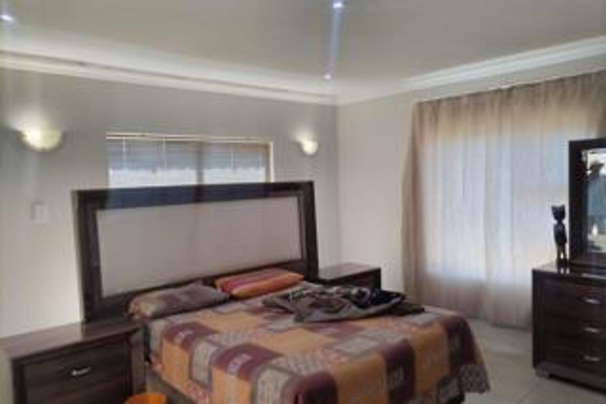 A spacious bedroom featuring recessed ceiling lighting, wall-mounted sconces, and window blinds, offering a neutral foundation for personal styling.