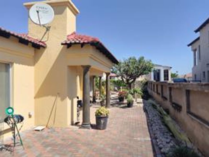 A paved outdoor patio area featuring decorative columns and a boundary wall, providing a functional space for outdoor living.