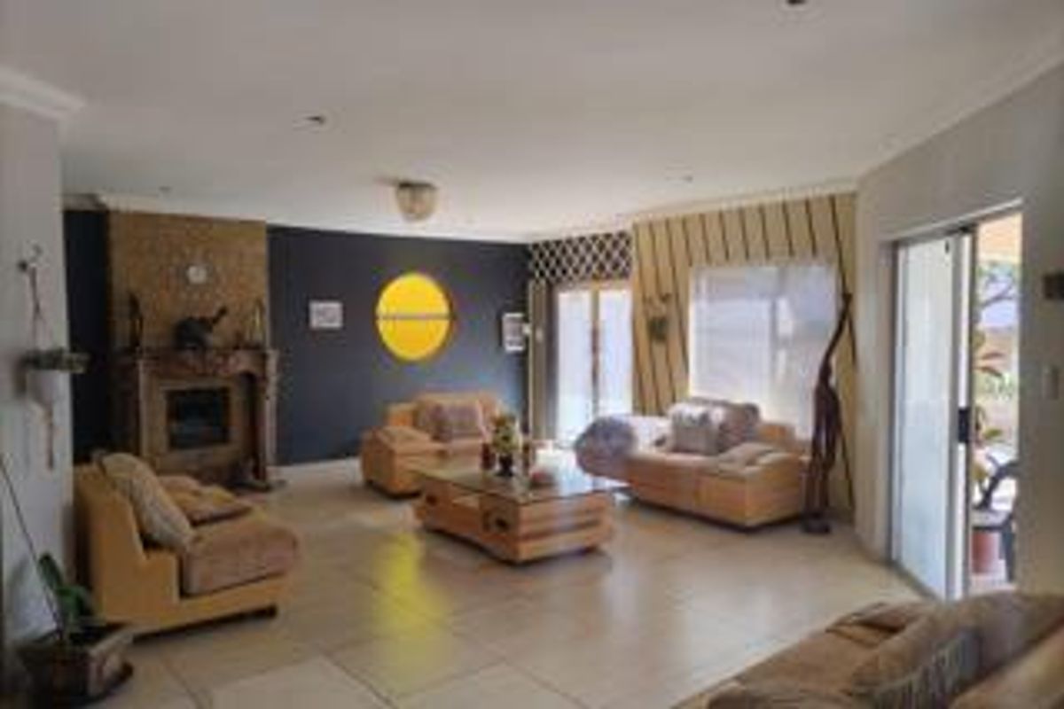 Spacious living room featuring a built-in fireplace, large format floor tiles, and sliding glass doors providing access to the outdoor area.