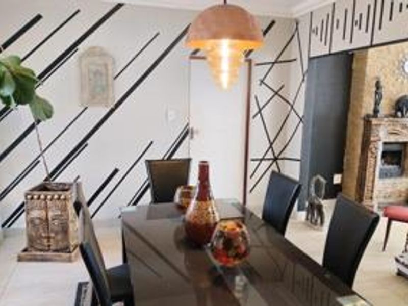 Dining room featuring a decorative feature wall, tiled flooring, and a built-in fireplace in the adjacent living area.