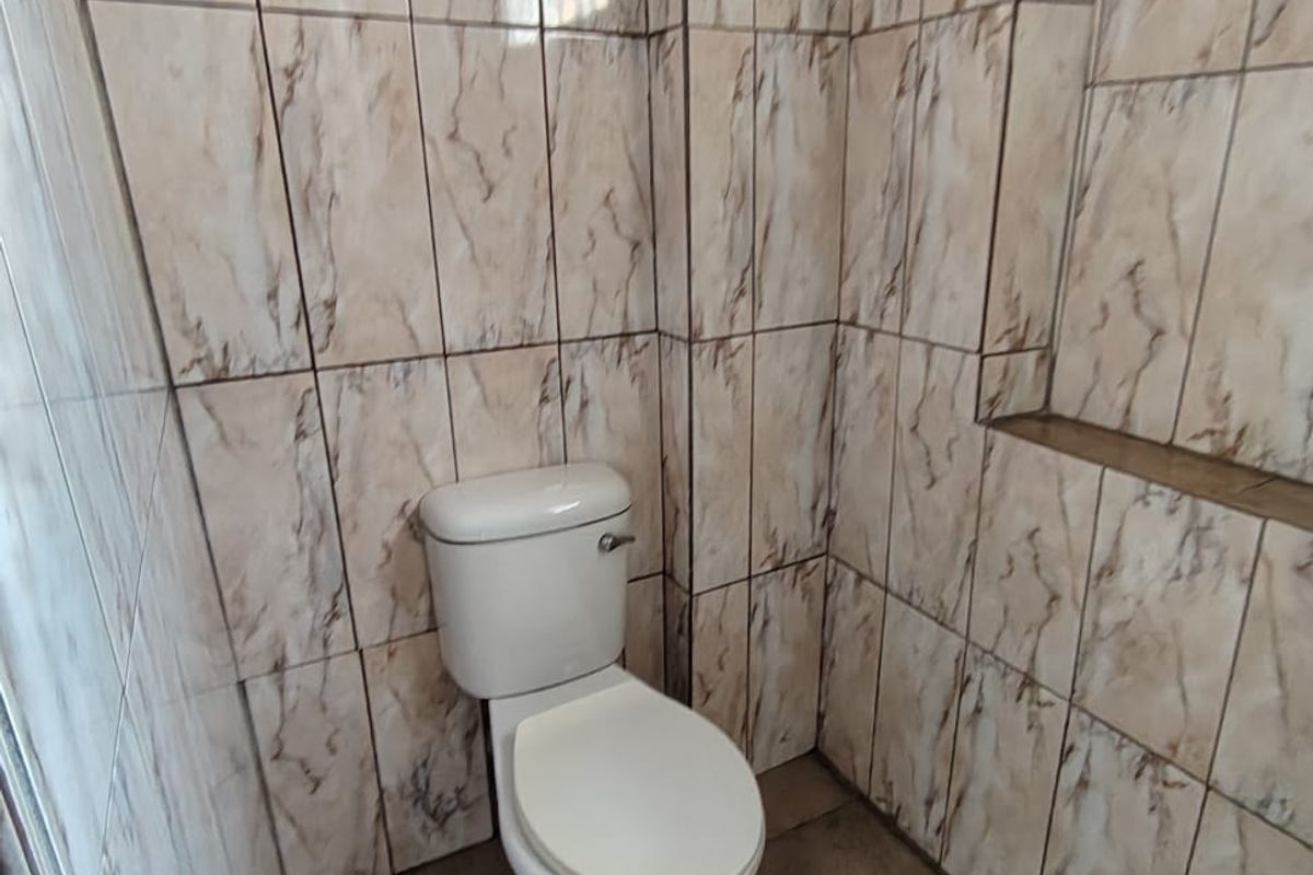 A small bathroom featuring full-height marble-effect wall tiling, a tiled floor, and a built-in recessed wall niche.