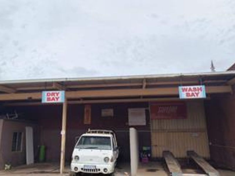 Commercial wash and dry bay facility featuring covered bays with concrete flooring and steel structural supports, suitable for automotive maintenance or cleaning operations.
