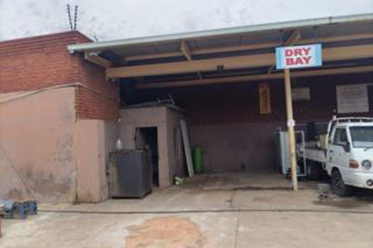 Commercial dry bay utility area featuring a concrete floor, metal roof structure, and brick exterior wall with integrated electric fencing.