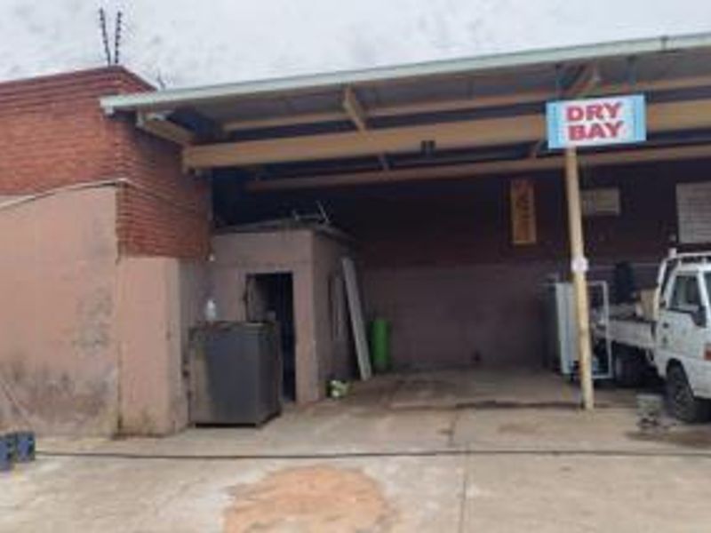 Commercial dry bay utility area featuring a concrete floor, metal roof structure, and brick exterior wall with integrated electric fencing.