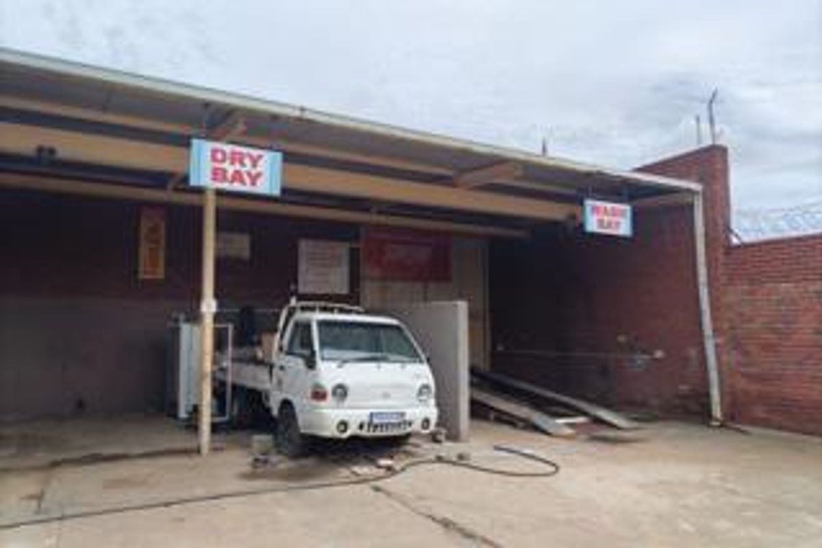 Commercial wash and dry bay facility featuring a covered structure with concrete flooring and brick boundary walls.