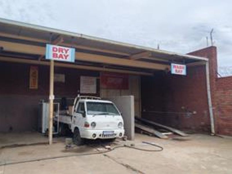 Commercial wash and dry bay facility featuring a covered structure with concrete flooring and brick boundary walls.