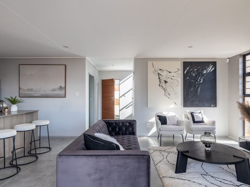 A modern, well-lit open-plan living area featuring sleek tiled floors, a functional kitchen island, and neutral finishes throughout.
