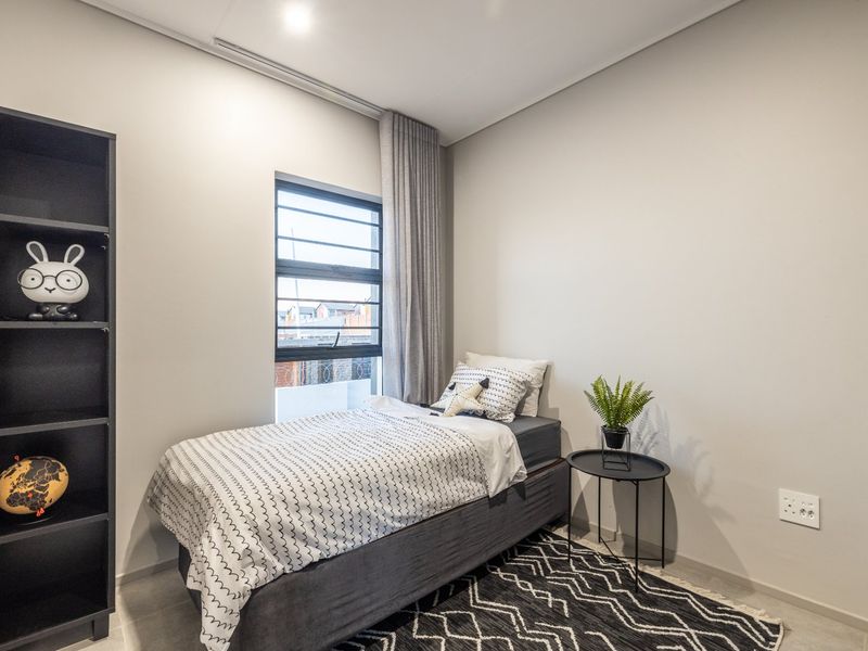 A well-maintained bedroom featuring neutral wall tones, tiled flooring, and a modern aluminium window frame with integrated curtain track.
