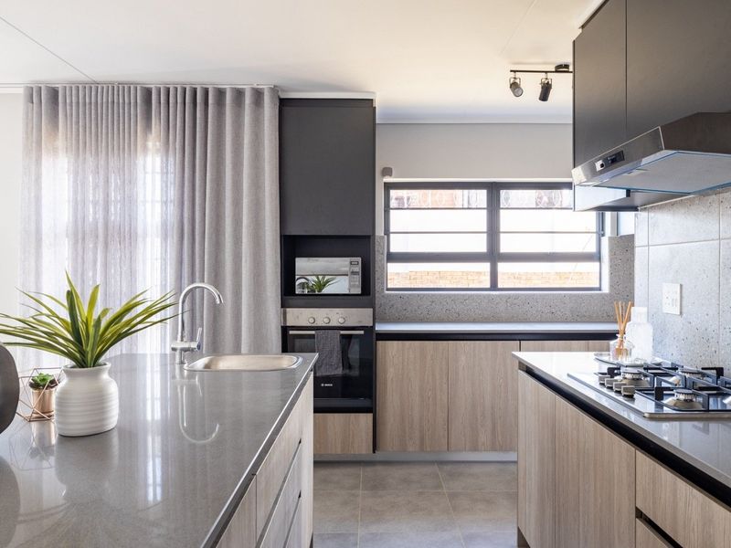Modern kitchen featuring a central island, stone countertops, built-in oven, gas hob, extractor fan, and sleek cabinetry with contemporary finishes.