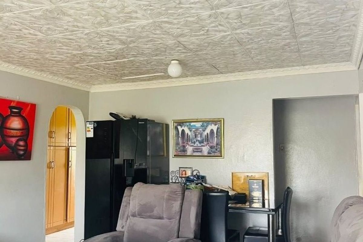 Living room featuring decorative ceiling tiles, tiled flooring, and an arched doorway leading to adjacent spaces.